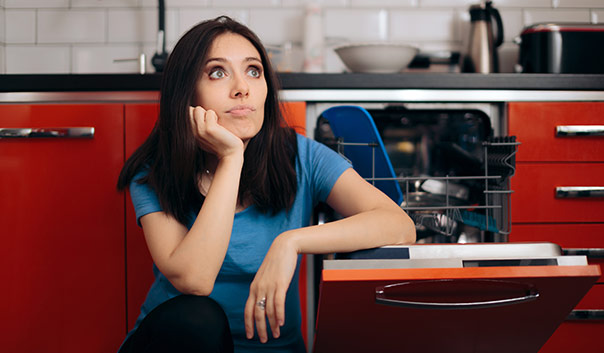 A women in the kitchen looking at a broken dishwasher